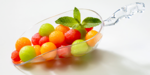 Un mélange de boules de melon et de pastèque dans une coupelle en verre avec une feuille de enthe sur le dessus.